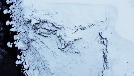 Snowy-volcanic-cliffs-in-Iceland,-aerial