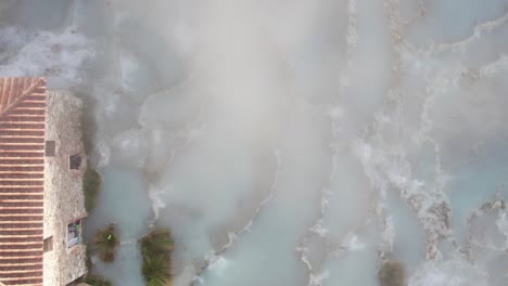 Hot-steam-gas-vapor-rising-from-blue-water-spring-in-rural-Italy,-tourist-destination,-top-down