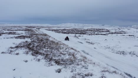 People-on-quad-bike-racing-through-winter-landscape-in-Iceland,-adventure