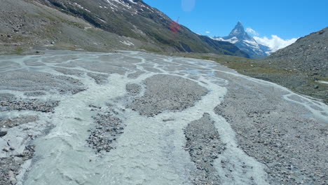 Flying-Close-Over-The-Findel-Glacier-And-Outwash-Plain-In-Switzerland-With-The-Majestic-Matterhorn-Summit-In-The-Background---FPV-drone-shot