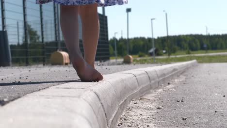 Girl-feet-walking-barefoot-on-sidewalk,-low-angle