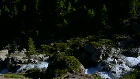 Panoramic-View-Above-The-Triftbach-River-In-Zermatt,-Switzerland-With-Cold-Water-Cascading-Through-The-Rocks---panning-shot