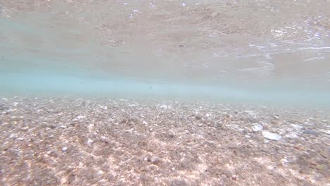 Slow-motion-underwater-view-of-small-waves-crashing-onto-a-white-sand-beach-on-Koh-Tao-Island-in-Thailand