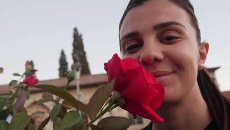 Female-Model-With-Red-Rose-Close-To-Face-Looking-into-Camera-And-Smiling