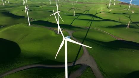 Orbiting-around-Wind-Turbine-spinning-in-slow-motion-against-green-hills-at-Wind-Turbine-Farm,-Northern-California