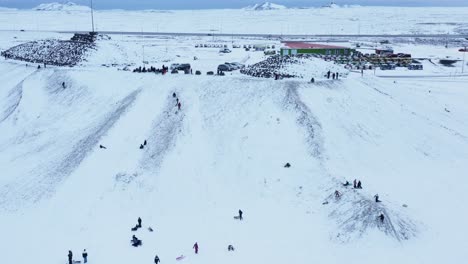 People-sliding-down-Kambur-tourist-attraction-in-Njarðvík,-Iceland,-aerial