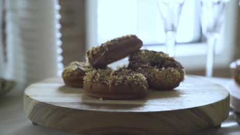 appetising-chocolate-donuts-with-sprinkles-stacked-on-wooden-board