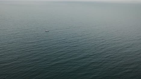Super-wide-high-aerial-view-of-small-sailboat-in-middle-of-vast-sea