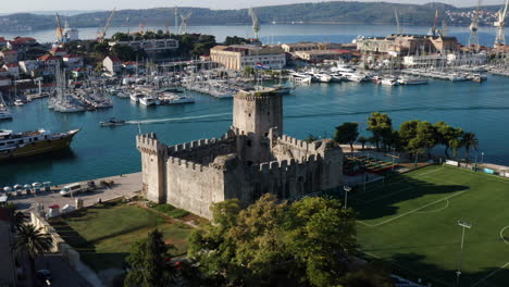 View-of-the-tower-of-Kamerlengo-Castle-and-the-Marina-of-the-old-Croatian-town-of-Trogir,-Dalmatia-region,-Croatia---drone-pullback