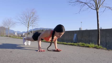 Fit-lean-young-woman-doing-pushup-exercise-outdoors-Wide-shot