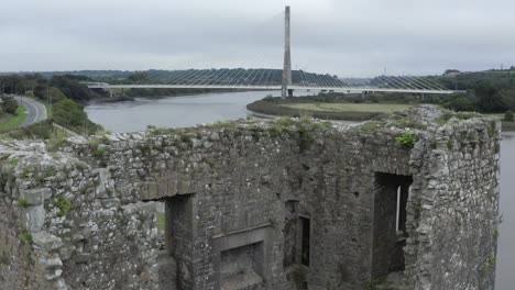 Rising-aerial-of-castle-ruin-reveals-modern-cable-stayed-bridge-beyond