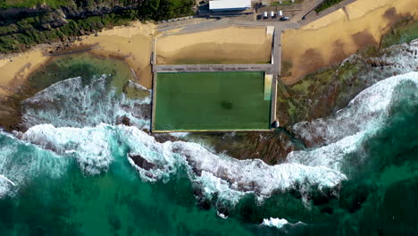 Lowering-drone-shot-of-ocean-bathes-at-Merewether,-New-South-Wales