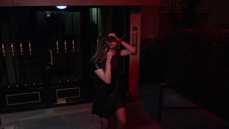 Young-Caucasian-Woman-Puts-On-Mask-Costume-With-Horns-And-Go-Into-Halloween-Party-At-Night