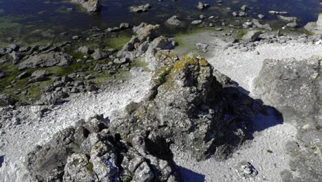 Aerial-view-around-rock-formations,-on-a-sunny-day,-on-Faro-island,-in-Gotland,-Sweden---High-angle,-orbit,-drone-shot