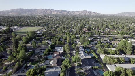 Aerial-side-view,-Northridge-community-of-homes,-with-pool,-clear-sky-of-mountains-in-distance