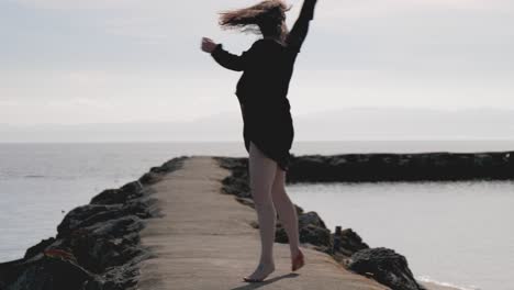 Woman-walks-barefoot-and-spins-around-several-time-on-cement-pier