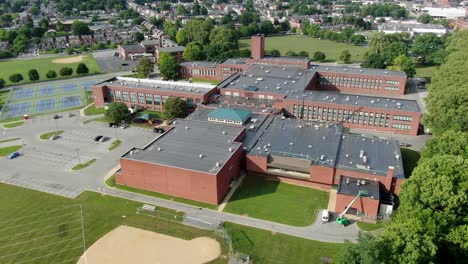 High-aerial-establishing-shot-of-school,-university,-college-campus-with-brick-academic-buildings-and-sports-fields,-tennis-courts