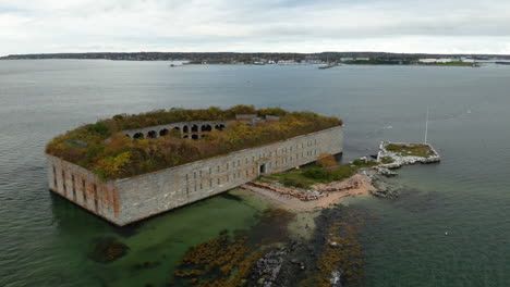 High-orbit-aerial-shot-of-Fort-Gorges-in-Casco-Bay-with-Portland,-Maine-in-the-background