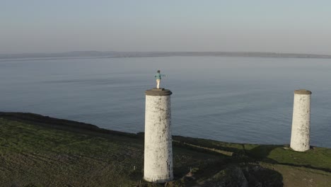 Retreating-aerial-of-Metal-Man-monument-beacon-tower,-Tramore-IRL