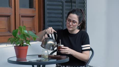 Revealing-shot-of-beautiful-brunette-pouring-down-water-and-drinking-a-mate,-A-beverage-from-Argentina-and-Uruguay