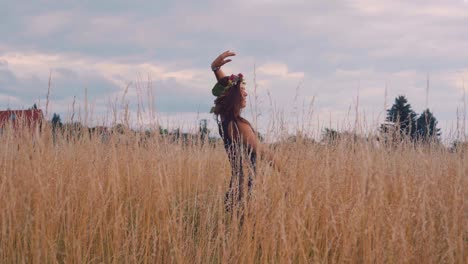A-pretty-young-happy-girl-grooving,-dancing-and-enjoying-the-beautiful-weather-and-feeling-the-summer-in-countryside-grain-fields-in-nature