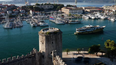 Croatian-Flag-At-The-Tower-of-Kamerlengo-Castle-WIth-Sailing-Boat-In-The-Sea-In-Trogir,-Croatia