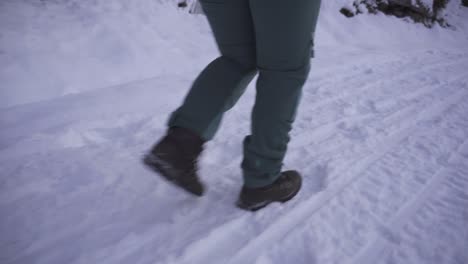 Female-Feet-In-Boots-Walking-On-Fresh-Snow-In-Winter---drone-low