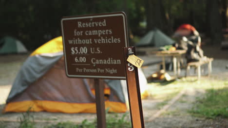 Static-view-of-a-reserved-area-with-blurred-signboard-indicating-the-amount-to-be-paid-for-camping-in-Glacier-NP-Campground-and-Creek,-United-States