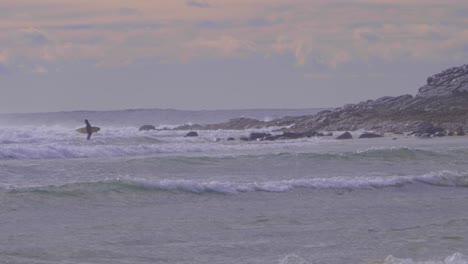 Surfer-Holding-A-Surfboard-In-The-Sea-With-Intense-Waves---Surfing-In-Crescent-Head,-NSW,-Australia---wide-shot