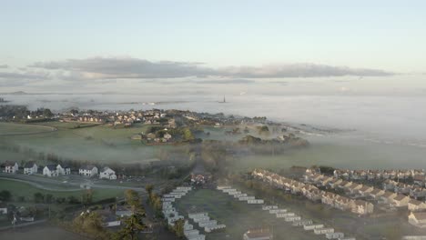 Foggy-aerial-evening-view-of-Irish-coastal-town-of-Tramore,-Waterford