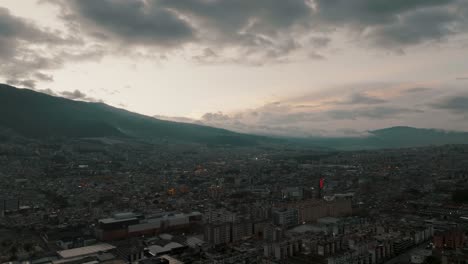 Aerial-drone-flight-showing-dusk-vibes-over-Quito-City-and-silhouette-of-mountain-range-in-background