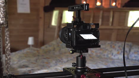 Tracking-shot-of-a-slider-camera-slowly-moving-on-a-rack-and-shooting-a-video-of-a-large-wooden-rustical-bedroom-with-a-big-bed-covered-with-old-fashioned-bedsheets