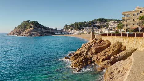 Tossa-de-Mar-bay-seen-from-the-castle-to-the-beach-with-coarse-sand-and-turquoise-blue-sea-water-old-walled-medieval-fishing-village-Mediterranean-sea