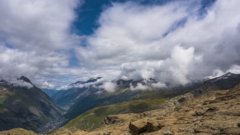 Zeitraffer-Von-Dicken-Wolken,-Die-An-Einem-Sonnigen-Tag-über-Dem-Dorf-Zermatt-In-Der-Schweiz-Mit-Nebelschwaden-Schweben---Hochwinkelaufnahme