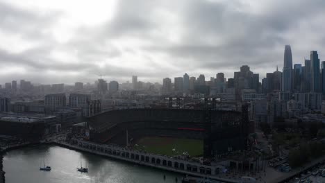 Aerial-wide-reverse-panning-shot-of-Oracle-Park-with-Downtown-San-Francisco-in-the-background-on-a-foggy-day