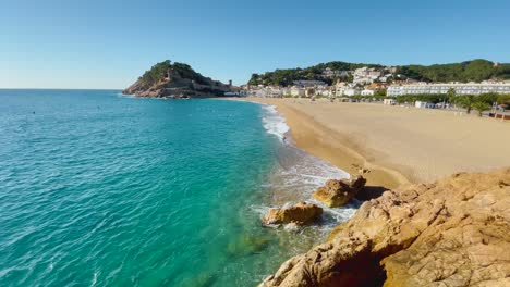 Tossa-de-Mar-bay-seen-from-the-castle-to-the-beach-with-coarse-sand-and-turquoise-blue-sea-water-old-walled-medieval-fishing-village-Mediterranean-sea