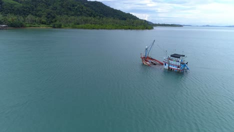 Barco-De-Pesca-Medio-Hundido-En-La-Orilla-De-Una-Isla-Desierta-Disparo-De-Drones-En-Movimiento-Lento