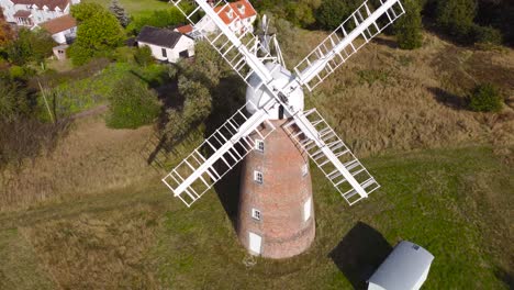 Billingford-Windmill-at-a-farm-land-area-with-house-in-Diss,-Norfolk---aerial-drone-flying-backward-shot
