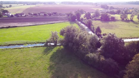 Aerial:-agricultural-land-area-with-drainage-canal-and-road-in-England---drone-shot