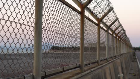 Pan-up-Chain-link-steel-wired--fence-on-sunset