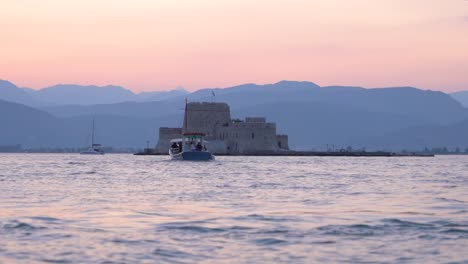 Beautiful-pink-sunset-at-Bourtzi-castle-seascape-with-a-boat,-Greece-Slow-Motion