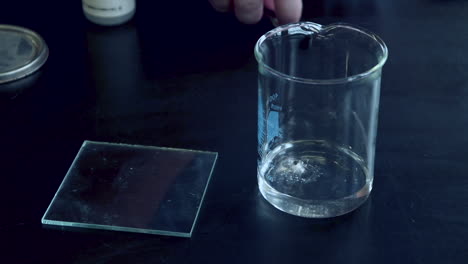 A-small-piece-of-sodium-metal-being-added-to-a-glass-beaker-with-water-and-reacts-vigorously-to-produce-flamable-hydrogen-gas-that-is-lit-by-a-burning-splint