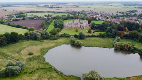 Aerial:-Framlingham-Castle-with-lake-and-agricultural-land-at-Suffolk,-England---drone-flying-backward-shot
