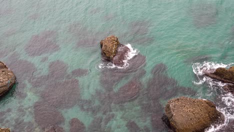 Looking-down-at-shallow-ocean-waters-with-rocks-sticking-out