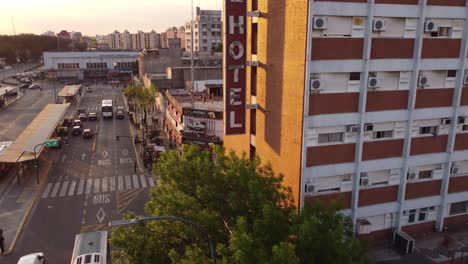 Aerial-shot-of-old-vintage-Hotel-in-Buenos-Aires-beside-Bus-Station-and-traffic-on-road-during-sunset-in-Buenos-Aires