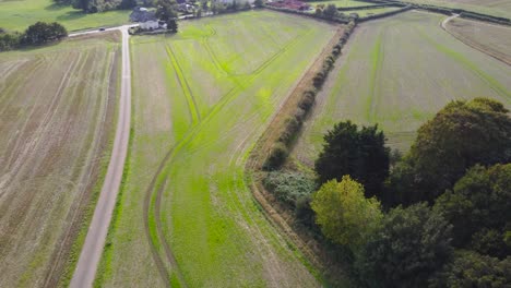 Aerial-agricultural-farmland-rural-village-field-with-highway-road-in-England---drone-flying-forward-shot