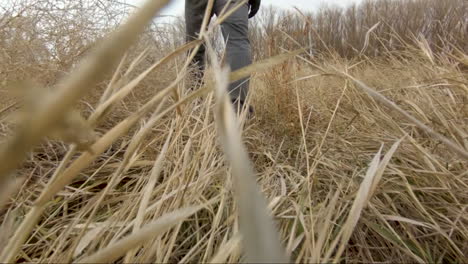 Close-up-of-feet-walking-through-tall-grass-and-weeds-in-slow-motion