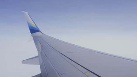 Passenger-POV-airplane-wing-flying-through-blue-skies-flight