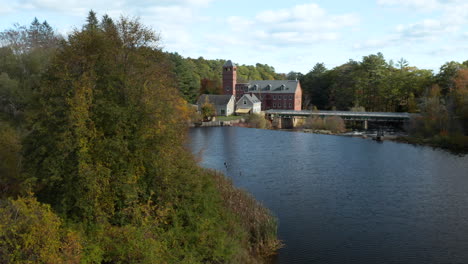 Gorgeous-side-tracking-aerial-shot-revealing-the-Sparhawk-Grist-Mill-near-the-Royal-River-in-Maine