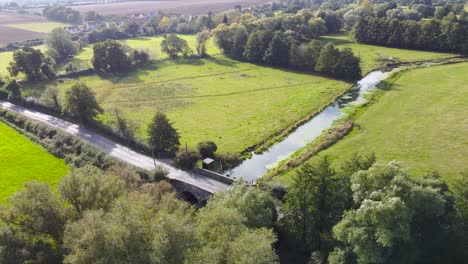 Countryside-road-with-canal-bridge-at-rural-area-in-England---aerial-drone-flying-shot